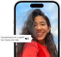 Un iPhone 15 con la funzione VoiceOver che descrive una fotografia: una persona con i capelli neri mossi che ride